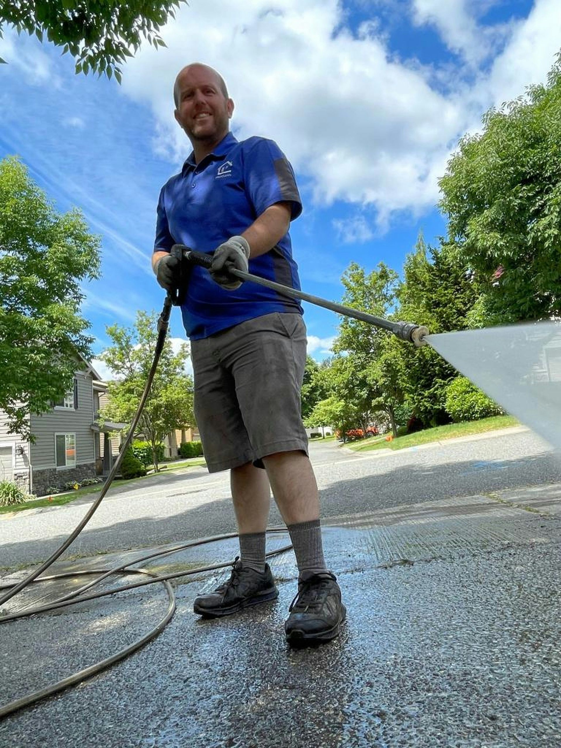 a man in a blue shirt is washing a driveway